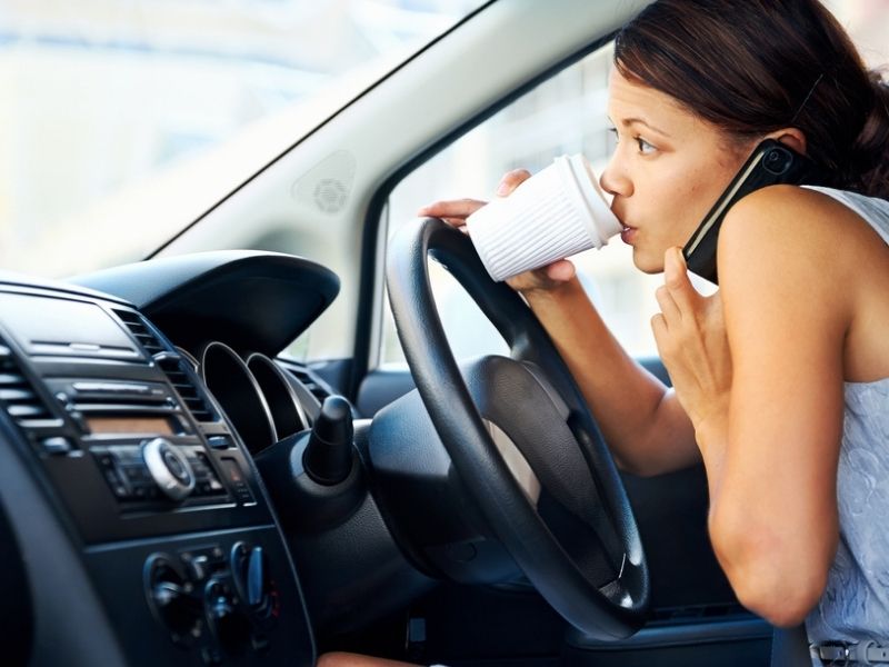 distracted woman driver drinking coffee and calling with driving